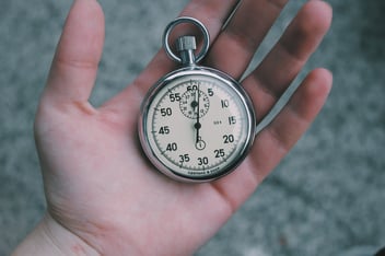 Hand holding stopwatch to record volunteer time in a volunteer hours log