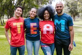 Four volunteer leaders wearing colorful t-shirts that spell 