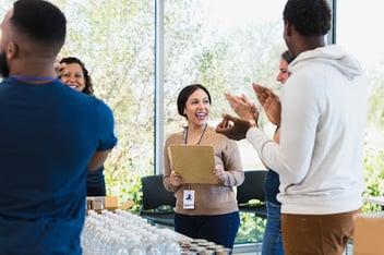 volunteer appreciation gifts concept; volunteers in a food bank applauding volunteer for a job well done