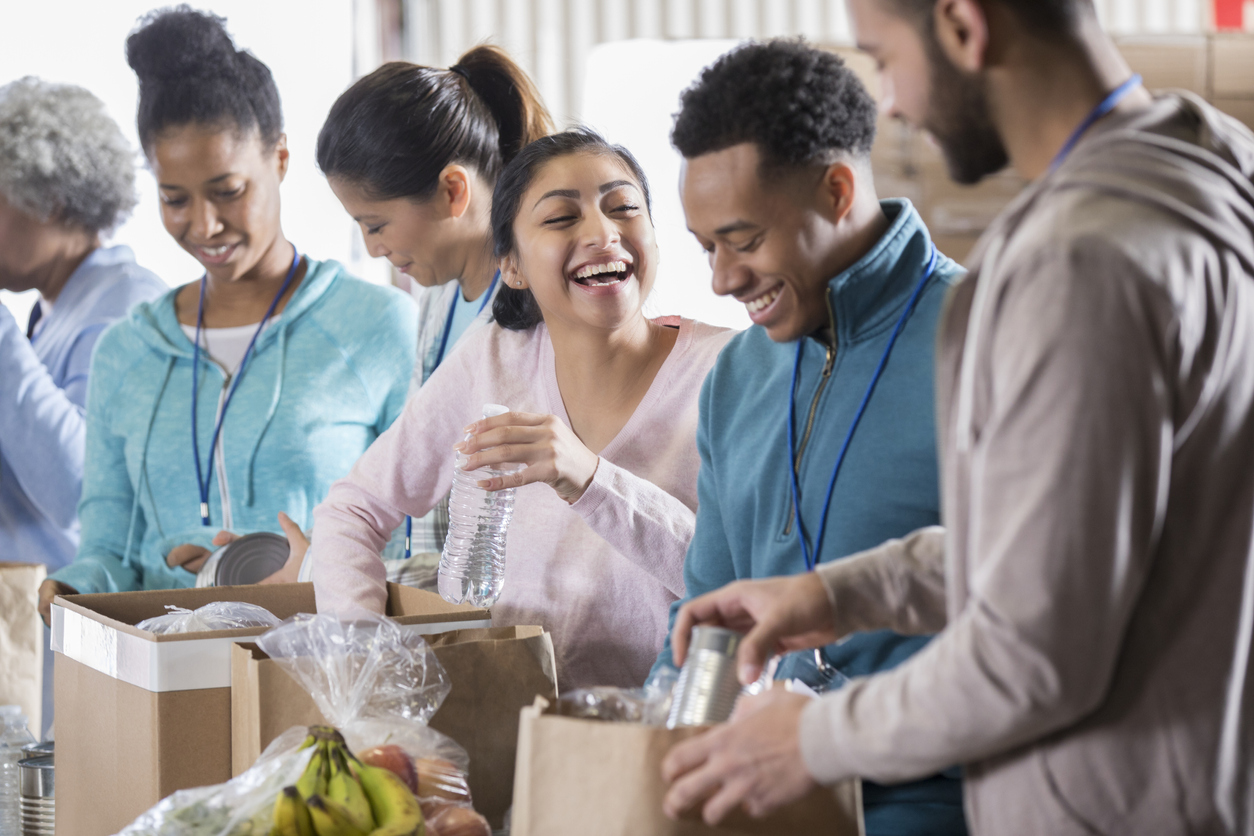 Group of corporate volunteers laughing while packing foods